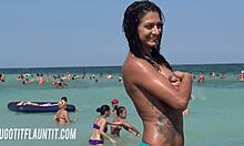 Isorintainen brunette, jolla on upea vartalo, esittelee rusketustaan rannalla