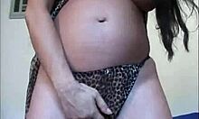 美しいブルネットがパンティ越しに妊娠したマンコをオナニーしています。