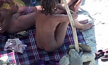 Красива брюнетка в сенките показва голото си тяло на нудистки плаж