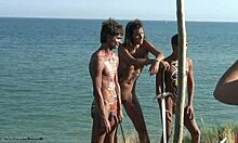 Tribal bodypaint hotties poserer med sverd og skitt på en strand